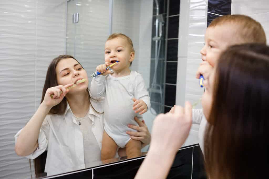 mother with baby brushing teeth in bathroom 2022 12 16 21 50 18 utc